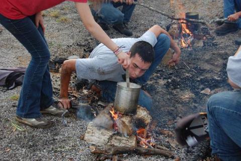 student blowing on fire to start it